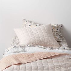 an unmade bed with pink and white pillows