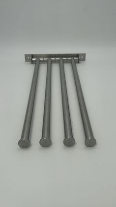 four stainless steel rods on a white surface with one metal bar in the middle and three are