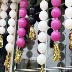 balloons and tassels are hanging in front of a store window with gold trim