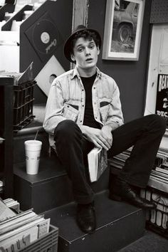 a man sitting on top of a set of stairs in a room filled with records