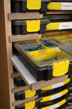 several yellow and black drawers in a storage unit with labels on the bottom, one for each drawer