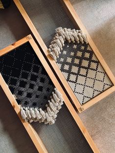 two pieces of weaving sitting on top of each other in wooden frames with black and white designs