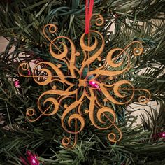 a wooden snowflake ornament hanging from a christmas tree