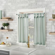 a kitchen with white brick walls and green curtains on the windowsill, along with wooden shelves