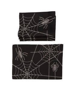 two spider webs on black napkins, one is folded and the other has a spider