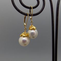 These lovely Edison pearls are near perfect with amazing glow. The pearls are capped with gold plate sterling flower caps. The ear wires are gold filled lever backs. Heirloom jewelry that is timeless and elegant. material:     Edison freshwater pearl, gold plate sterling flower cap and ear wires. dims:           1 and 1/4 inches long. pearl size:   10 mm. pearl type:  Edison freshwater. Gold Round Pearl Earrings With French Hook, Classic Handmade Yellow Gold Pearl Earrings, Gold Akoya Pearl Earrings With Ear Wire, Handmade Classic Yellow Gold Pearl Earrings, Gold Pearl Lever Back Earrings For Formal Events, Heirloom Jewelry, Edison Pearls, Freshwater Pearl Earrings, Heirlooms Jewelry