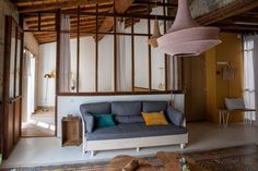 a living room filled with furniture next to a wooden ceiling mounted light hanging from the ceiling