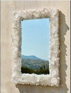 a mirror hanging on the side of a wall with mountains in the backround