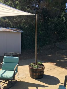 a patio with chairs and an umbrella on top of it, next to a potted plant