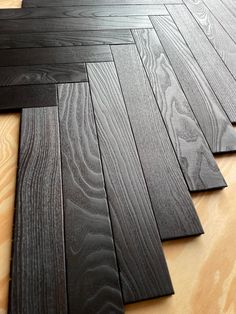 black wood flooring laid out on top of a wooden floor with different types of boards