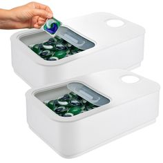 two white plastic containers filled with green and blue glass rocks, one being opening the lid