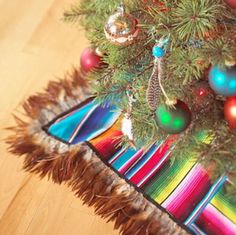 a colorful christmas tree skirt with ornaments hanging from it's sides on a wooden floor