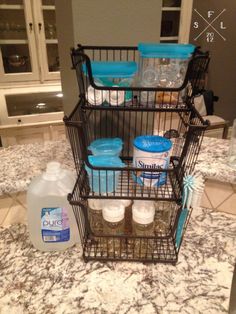 three wire baskets filled with bottles and containers sitting on top of a marble countertop