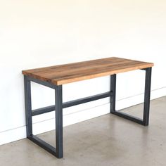 a wooden table with metal legs against a white wall