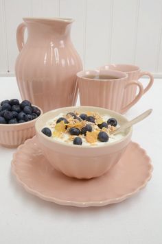 a bowl of oatmeal with blueberries in it and two cups on the side