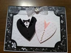 a card with two pieces of paper in the shape of heart and tuxedo