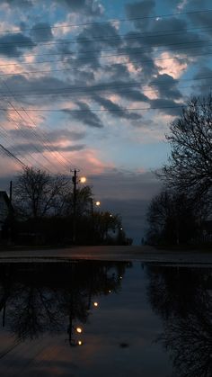 the sky is reflecting in the water at dusk, with power lines and telephone poles visible