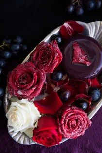 red and white flowers are arranged on a plate with chocolates in the shape of a triangle