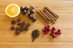 an assortment of spices on a cutting board with oranges, cinnamon sticks and star anise