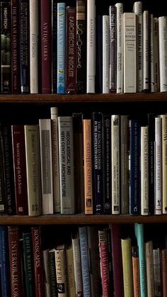 a bookshelf filled with lots of different colored books on top of wooden shelves