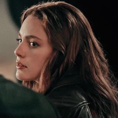 a close up of a person wearing a leather jacket and looking off into the distance