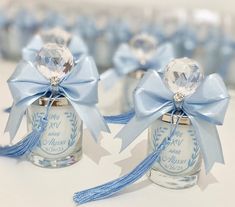 two small glass bottles with blue ribbons and bows on them are sitting next to each other