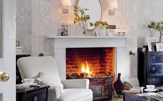 a living room filled with furniture and a fire place in front of a mirror on the wall