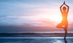 a woman doing yoga on the beach at sunset