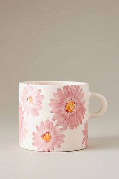 a pink and white flowered coffee cup sitting on top of a table