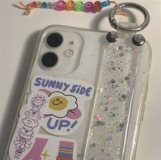 an iphone case with some stickers on it and a keychain next to it