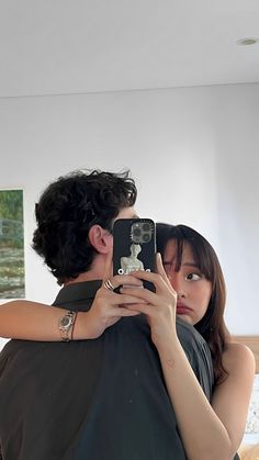 a man holding a woman in his arms while she takes a selfie with her cell phone