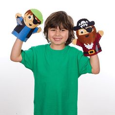 a young boy holding up two pirate puppets