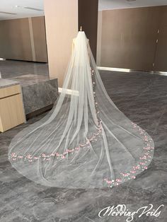 a wedding veil with pink flowers is on display in an empty room at a hotel