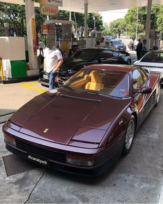 a maroon sports car parked at a gas station