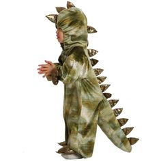 a little boy in a dinosaur costume is standing with his hands out to the side