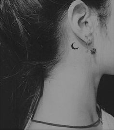 black and white photograph of a woman's ear with a crescent tattoo on it