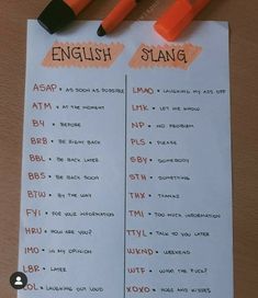 two orange markers on top of a white paper with english and spanish words attached to it