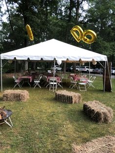 a tent set up with hay bales and balloons in the shape of numbers on it