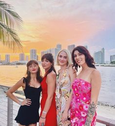 three beautiful women standing next to each other on a pier in front of the ocean