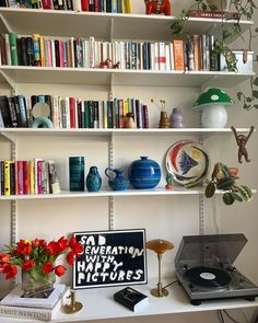 a record player sitting on top of a table next to a shelf filled with books