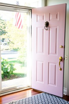 a pink door with an american flag hanging on it's side next to a blue and white rug