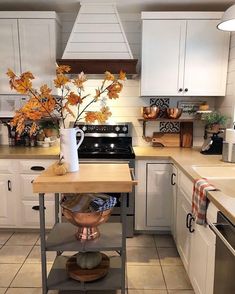 a kitchen with white cabinets and an island in the middle, filled with fall leaves