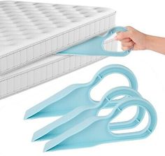 a person is holding scissors near a mattress and another item that looks like it has been opened