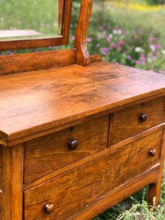 an old wooden dresser with a mirror on it's top and drawers below the drawer