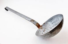 an old metal strainer sitting on top of a white table next to a knife