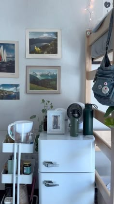 a white dresser sitting next to a shelf filled with pictures and other items on top of it