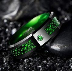 a green ring sitting on top of a rock next to a black stone covered ground