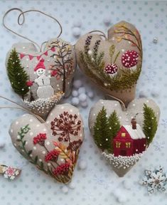 four heart shaped ornaments on a table with snowflakes and decorations in the background