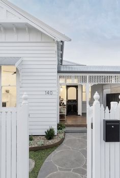 a white house with a gate in front of it and a walkway leading to the door