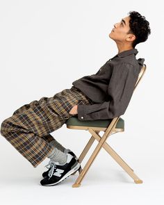 a young man sitting on top of a wooden chair